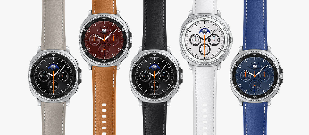 Five smartwatches with round silver-tone cases are arranged side by side on a light gray background. Each watch has a different strap color: beige, tan, black, white, and blue, with various dial designs including analog-style faces and moon-phase indicators.